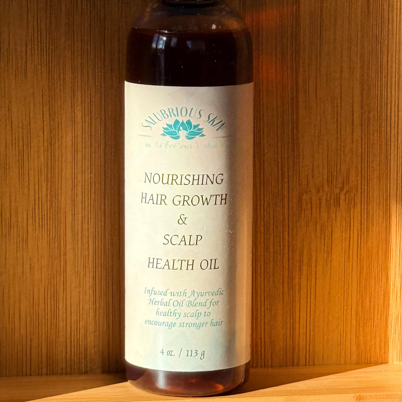 Bottle of nourishing hair growth and scalp health oil on a wooden surface