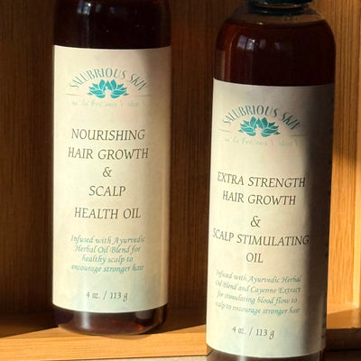Two bottles of Nourishing Hair Oil on a wooden shelf.