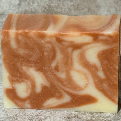Swirled pink and white soap bar on a textured surface
