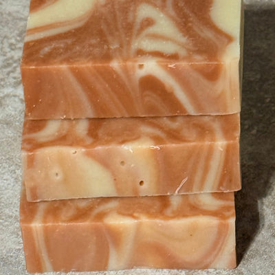 Stack of three soap bars with pink and white swirled pattern on a textured surface